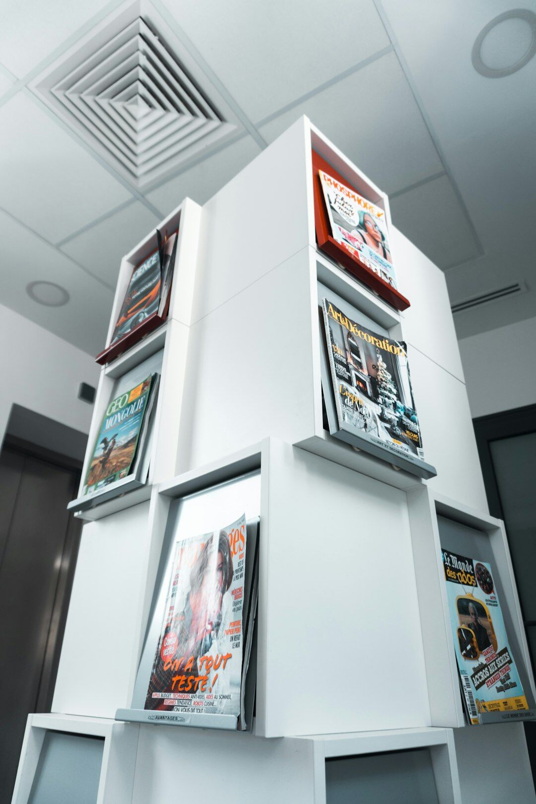 Stack of glossy magazines with a tablet showing exclusive articles